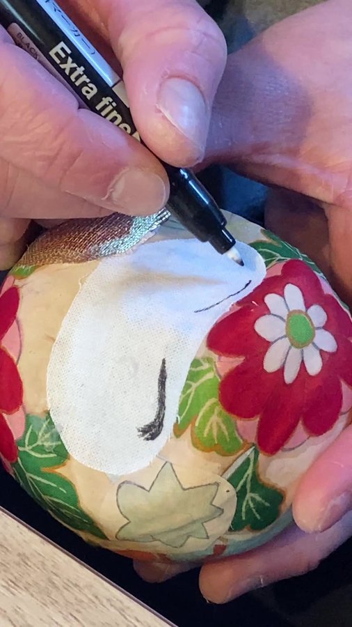 Drawing the face on a fabric-covered daruma in Chofu